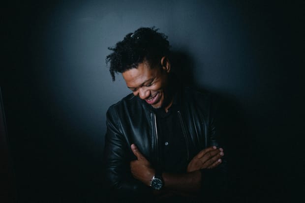 Lechon Kirb in a black leather jacket, head down, laughing