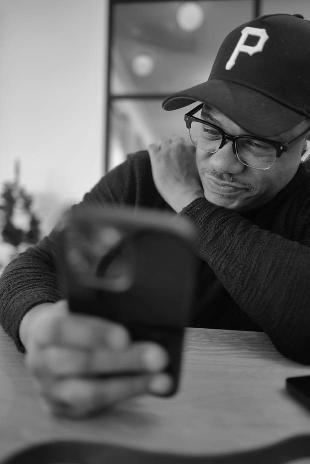 Lechon Kirb leaning on a table over a phone, working, photographed in black and white
